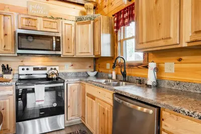a kitchen with wooden cabinets and a stove and a sink at Cheerful Cabin Nestled in Serene Wooded Ravine in Logan