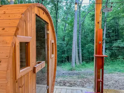 a wooden out house with a door in the woods at Cheerful Cabin Nestled in Serene Wooded Ravine in Logan