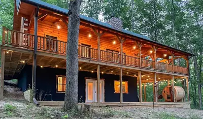 a large wooden house with a large deck at Cheerful Cabin Nestled in Serene Wooded Ravine in Logan