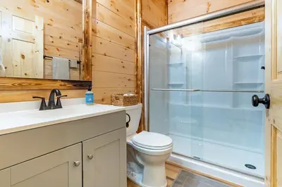 a bathroom with a toilet and a glass shower at Cheerful Cabin Nestled in Serene Wooded Ravine in Logan