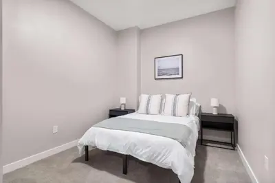 a white bedroom with a bed and two night stands at CozySuites at Textile in Cincinnati