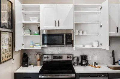 a kitchen with white cabinets and a microwave at CozySuites at Textile in Cincinnati