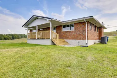 a brick house with a deck on a grass field at 10 Mi to Red River Gorge Peaceful Rural Getaway! in Campton