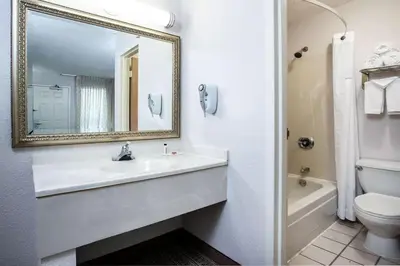 a bathroom with a sink and a toilet and a mirror at Three Rivers Motel in Fort Wayne