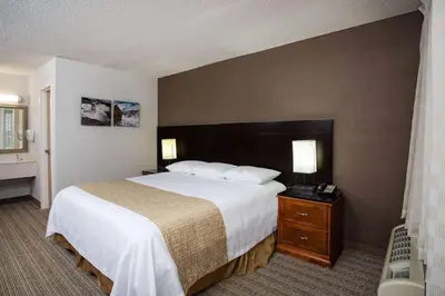 a hotel room with a large bed and a nightstand at Three Rivers Motel in Fort Wayne