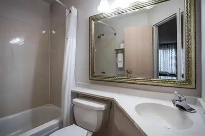 a bathroom with a toilet and a sink and a mirror at Three Rivers Motel in Fort Wayne