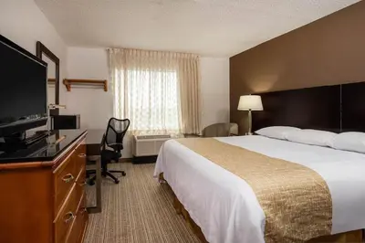 a hotel room with a bed and a flat screen tv at Three Rivers Motel in Fort Wayne