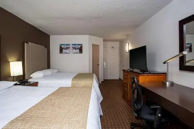 a hotel room with two beds and a desk with a television at Three Rivers Motel in Fort Wayne