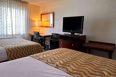 a hotel room with two beds and a flat screen tv at Three Rivers Motel in Fort Wayne
