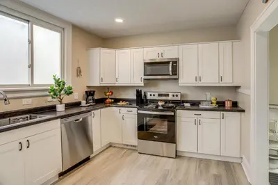 a kitchen with white cabinets and stainless steel appliances at 1 Mi to Cedar Point Family Getaway with Porch! in Sandusky