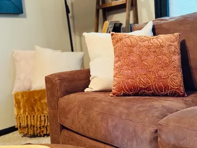 a brown couch with an orange pillow on it at Luxurious 1875 centrally located Canton Akron home, expansive primary & sunset view in Uniontown