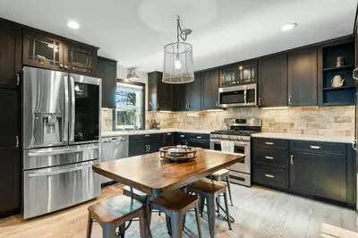 a kitchen with black cabinets and a wooden table at Luxurious 1875 centrally located Canton Akron home, expansive primary & sunset view in Uniontown