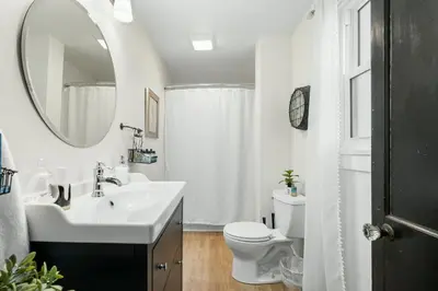 a bathroom with a sink and a toilet and a mirror at Luxurious 1875 centrally located Canton Akron home, expansive primary & sunset view in Uniontown