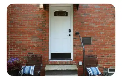 a brick house with a white door and two benches at Shaker Heights Apartment near Cleveland Clinic in Shaker Heights