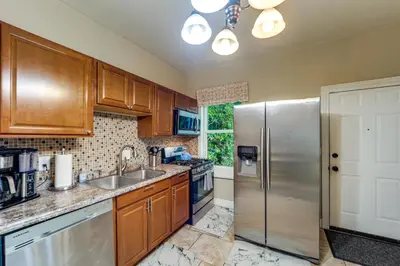 a kitchen with wooden cabinets and a stainless steel refrigerator at Walk to University of Cincinnati Historic Home! in Cincinnati