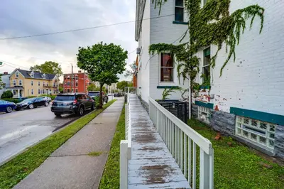 a rain soaked sidewalk next to a white house at Walk to University of Cincinnati Historic Home! in Cincinnati