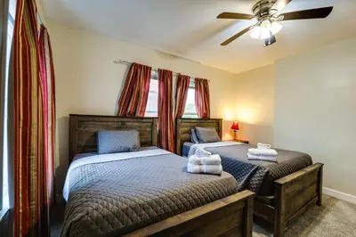 two twin beds in a bedroom with a ceiling fan at Walk to University of Cincinnati Historic Home! in Cincinnati