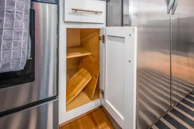 an open cabinet in a kitchen next to a refrigerator at OTR by TQL, Smart TVs, Lux King Bed, Fast Wifi, Sleeps 3ppl, 2nd Fl in Cincinnati