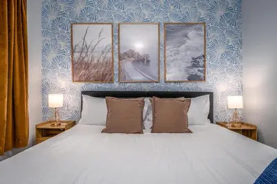 a bedroom with a bed with three pictures on the wall at OTR by TQL, Smart TVs, Lux King Bed, Fast Wifi, Sleeps 3ppl, 2nd Fl in Cincinnati