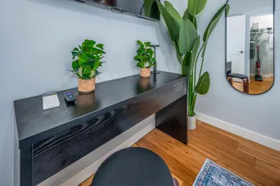 a black desk in a room with potted plants at OTR by TQL, Smart TVs, Lux King Bed, Fast Wifi, Sleeps 3ppl, 2nd Fl in Cincinnati