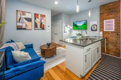 a living room with a blue couch and a kitchen at OTR by TQL, Smart TVs, Lux King Bed, Fast Wifi, Sleeps 3ppl, 2nd Fl in Cincinnati