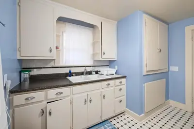 a kitchen with white cabinets and a sink at Historic 1 Bdr across from Lakeside Park in Fort Wayne
