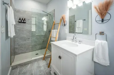 a white bathroom with a shower and a sink at OTR by TQL, Lux King Bed, Fast Wifi, Sleeps 6ppl, 1st Fl in Cincinnati