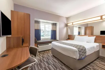 a hotel room with a bed and a desk and a television at Microtel Inn & Suites by Wyndham Cadiz in Cadiz