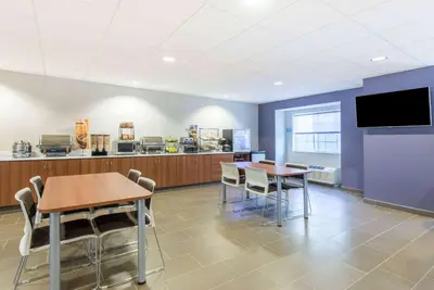 a cafeteria with two tables and chairs and a tv at Microtel Inn & Suites by Wyndham Cadiz in Cadiz