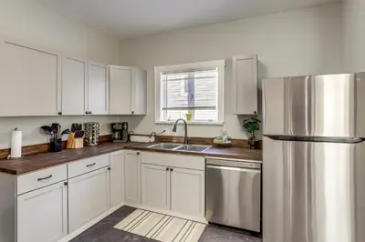 a kitchen with white cabinets and a stainless steel refrigerator at Walk to Port Clinton Lighthouse Home with Deck! in Port Clinton