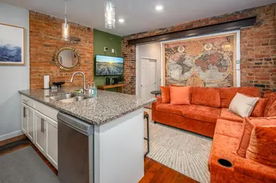 a kitchen and living room with a red couch at OTR by TQL, Private Rooftop, King Beds, Sleeps 8ppl, Wifi in Cincinnati