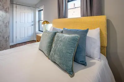 a bedroom with a bed with a yellow headboard and pillows at OTR by TQL, Private Rooftop, King Beds, Sleeps 8ppl, Wifi in Cincinnati