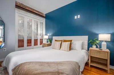 a bedroom with a large bed with a blue wall at OTR by TQL, Private Rooftop, King Beds, Sleeps 8ppl, Wifi in Cincinnati