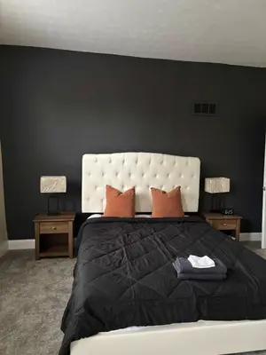 a black bedroom with a large bed with orange pillows at Family Home Minutes from Downtown Cincy in Cincinnati
