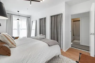 a white bedroom with a large bed and windows at Riverfront Retreat - 2 Units - 3BR - Free Parking in Cleveland