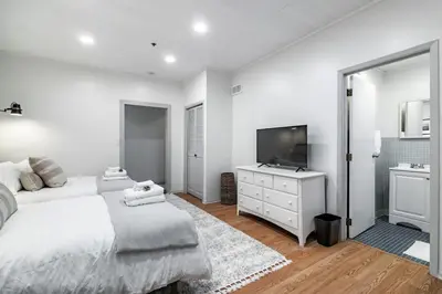 a white bedroom with a bed and a television at Riverfront Retreat - 2 Units - 3BR - Free Parking in Cleveland