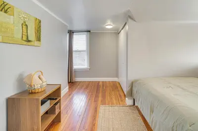 a bedroom with a bed and a table and a window at Walk to Coventry Village Charming Top-Floor Unit! in Cleveland Heights