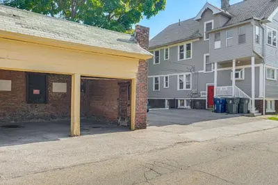 a brick building with a garage in a street at Walk to Coventry Village Charming Top-Floor Unit! in Cleveland Heights