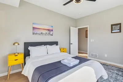 a white bedroom with a bed and a yellow night stand at Family Fun Near Cedar Point - Rooftop Lake Views in Sandusky