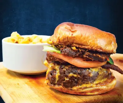 a hamburger on a cutting board next to a bowl of macaroni at Embassy Suites by Hilton Akron Canton Airport in North Canton