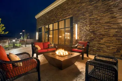 a patio with a fire pit and chairs and a building at Embassy Suites by Hilton Akron Canton Airport in North Canton