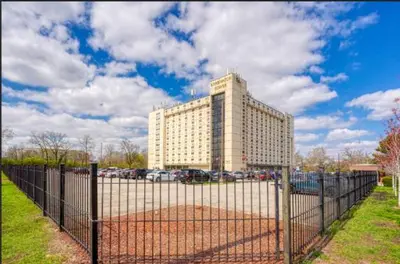 a building with a fence in front of a parking lot at Right by OSU Stadium and Schottenstein Ctr - Walk to your game or concert in Columbus