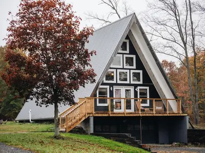 a large black house with a porch and a deck at Cozy A-Frame Getaway Minutes from Nelson Ledges