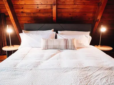 a large white bed with two lamps on two tables at Cozy A-Frame Getaway Minutes from Nelson Ledges