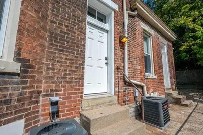 a brick house with a white door and a trash can at Queen City Suites 2 - For 4 in Cincinnati