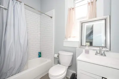 a white bathroom with a toilet and a sink at Queen City Suites - For 7 in Cincinnati