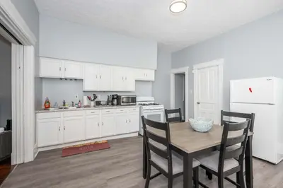 a kitchen with white cabinets and a table and chairs at Queen City Suites 1 - For 3 in Cincinnati