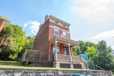 a red brick house with a balcony on the front at Queen City Suites 1 - For 3 in Cincinnati