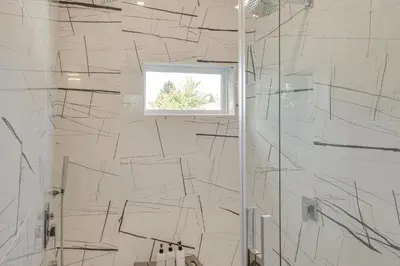 a bathroom with a shower with black and white tiles at 7 Mi to Dtwn and Lake Erie Sleek Cleveland Apt! in Cleveland