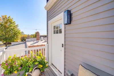 a house with a white door and a balcony with flowers at 7 Mi to Dtwn and Lake Erie Sleek Cleveland Apt! in Cleveland